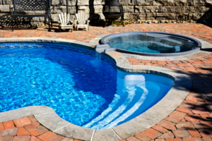 Fiberglass pool with spa. Outdoor inground residential swimming pool in backyard with spa. Viking Pools & Outdoor Living